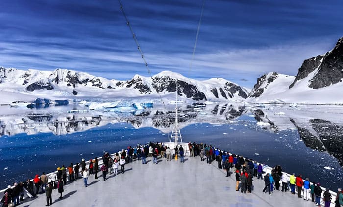 Пассажиры на носу пассажирского круизного лайнера около побережья Антарктиды