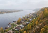 Панорама небольшого старинного волжского городка с высокого берега в золотую осень